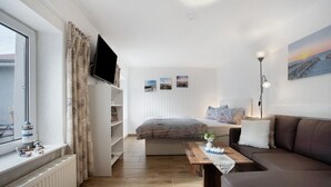 Ett modernt vardagsrum med en soffa, ett soffbord, en tv och ett fönster med gardiner.
