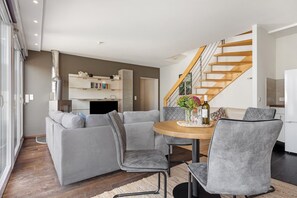 Un salon moderne comprenant un canapé, des fauteuils, une table à manger et un escalier.