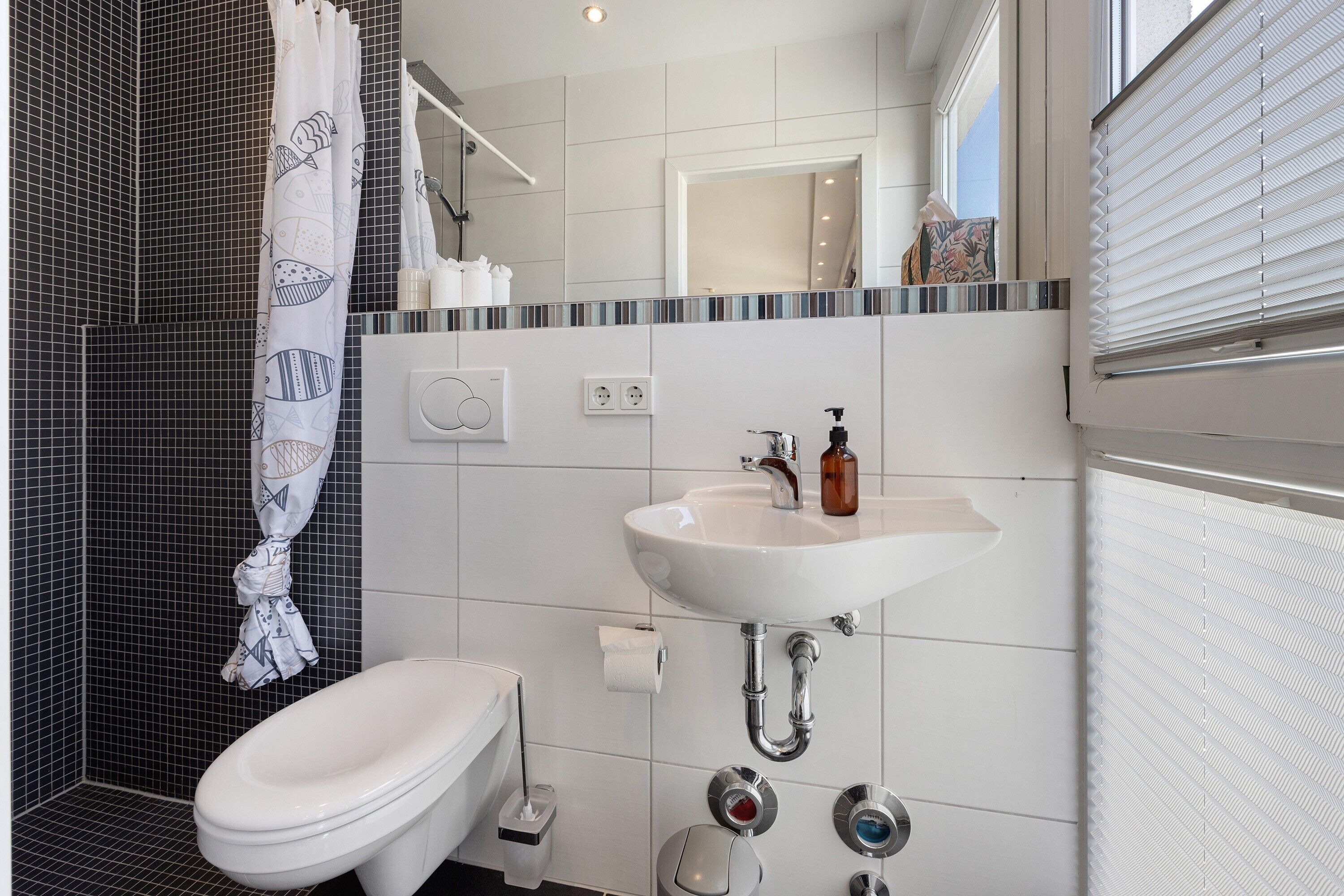 Une salle de bain moderne avec un lavabo blanc, des toilettes et un rideau de douche.
