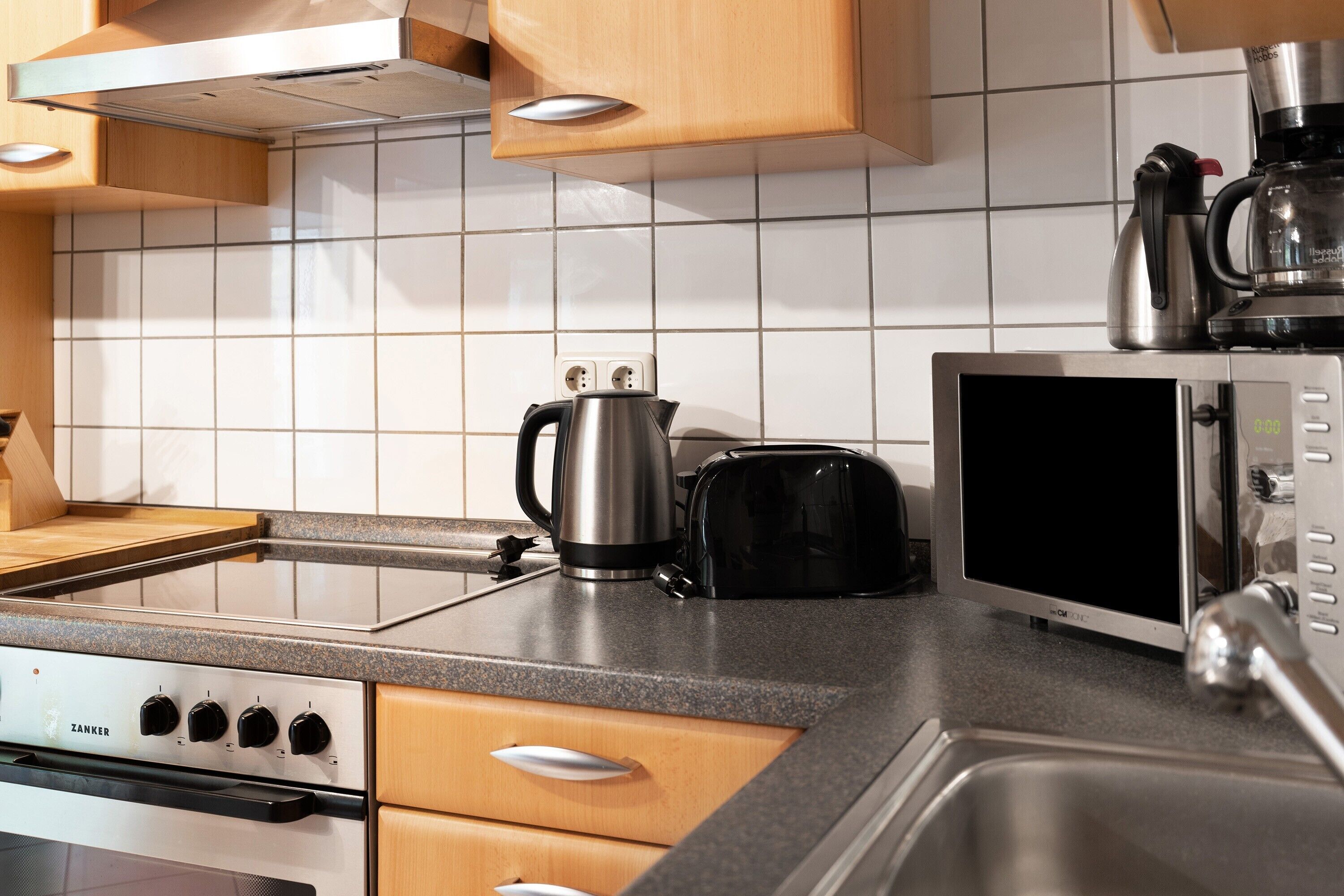 A kitchen with a Zanker stove, a coffee maker, a toaster, and a microwave.