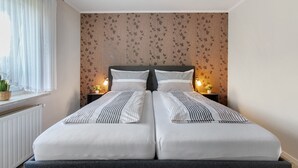 A double bed with striped bedding, a dark headboard, and two bedside lamps. - Apartment 'Ferienwohnung Sawade' with Private Terrace, Shared Garden and Wi-Fi (Schafstedt)