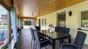 An outdoor patio with a glass-top table, wicker chairs, and a potted plant. - Apartment 'Ferienwohnung Sawade' with Private Terrace, Shared Garden and Wi-Fi (Schafstedt)
