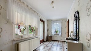 A hallway with patterned walls, a radiator, a window with a curtain, and a door. - Apartment 'Ferienwohnung Sawade' with Private Terrace, Shared Garden and Wi-Fi (Schafstedt)