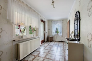 A hallway with patterned walls, a radiator, a window with a curtain, and a door. - Apartment 'Ferienwohnung Sawade' with Private Terrace, Shared Garden and Wi-Fi (Schafstedt)