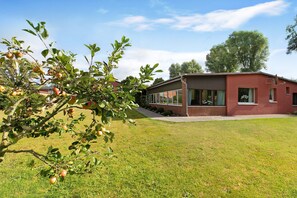 Un bâtiment moderne avec une façade rouge, de grandes fenêtres et une pelouse bien entretenue.