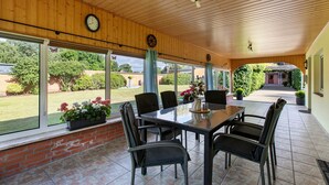 A covered patio area with a table and chairs, large windows, and a view of the garden. - Apartment 'Ferienwohnung Sawade' with Private Terrace, Shared Garden and Wi-Fi (Schafstedt)