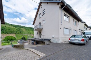 Ein zweistöckiges Gebäude mit Balkon, einem geparkten Auto davor und einem befestigten Einfahrt.