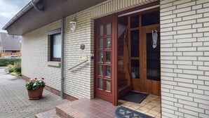 A building with a brick exterior, a wooden door with glass panels, a small window, and a potted plant on the ground. - Apartment 'Haus Stoldt, Wohnung 2' with Shared Terrace, Shared Garden and Wi-Fi (Meldorf)