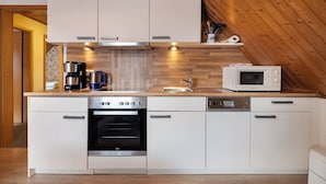 A modern kitchen with white cabinetry, a built-in oven, a microwave, and a coffee maker. - Apartment 'Haus Stoldt, Wohnung 1' with Shared Terrace, Shared Garden and Wi-Fi (Meldorf)