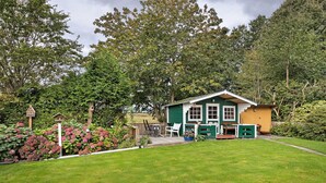 A house with a green exterior, a porch, and a small garden area. - Apartment 'Haus Stoldt, Wohnung 1' with Shared Terrace, Shared Garden and Wi-Fi (Meldorf)