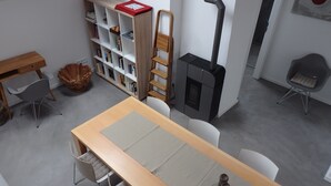 A modern room with a wooden table, chairs, a bookshelf, a ladder, and a fireplace. - Apartment 'Fewoimdorf' with Wi-Fi (Wertheim)