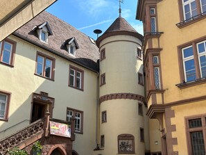 Ein Gebäude mit einem Turm, zahlreichen Fenstern und einer Treppe mit einer verzierten Brüstung.