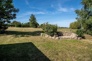 Un espace extérieur verdoyant, avec une structure en pierre, des arbres et un ciel bleu dégagé.