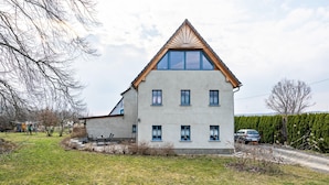 Une maison à deux étages, dotée d’un toit en pente, de nombreuses fenêtres et d’un garage apparent.