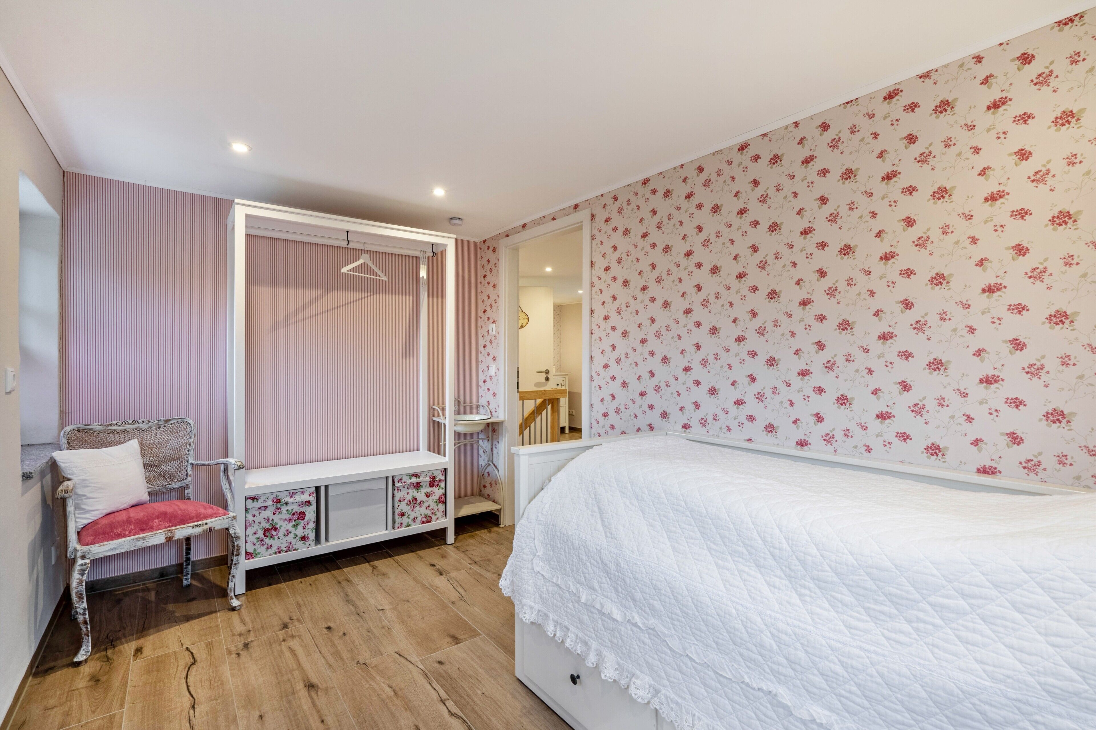 A bedroom with a bed, a vanity, a chair, and a wardrobe.