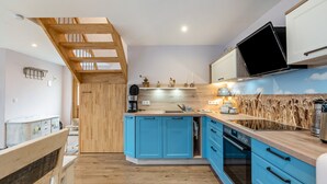 Une cuisine moderne avec des armoires bleues, un plafond en bois et un four encastré.