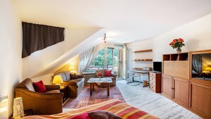 Ein Zimmer mit einem Bett, einem Schlafsofa, einem Tisch, einem Fernseher und einem Schrank.