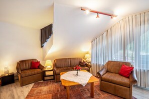Una sala de estar con un sofá, un sillón y una mesita con un florero.