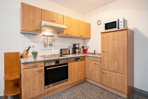 Eine Küche mit Holzausstattung, einer Mikrowelle, einer Kaffeemaschine und einem Geschirrspüler.