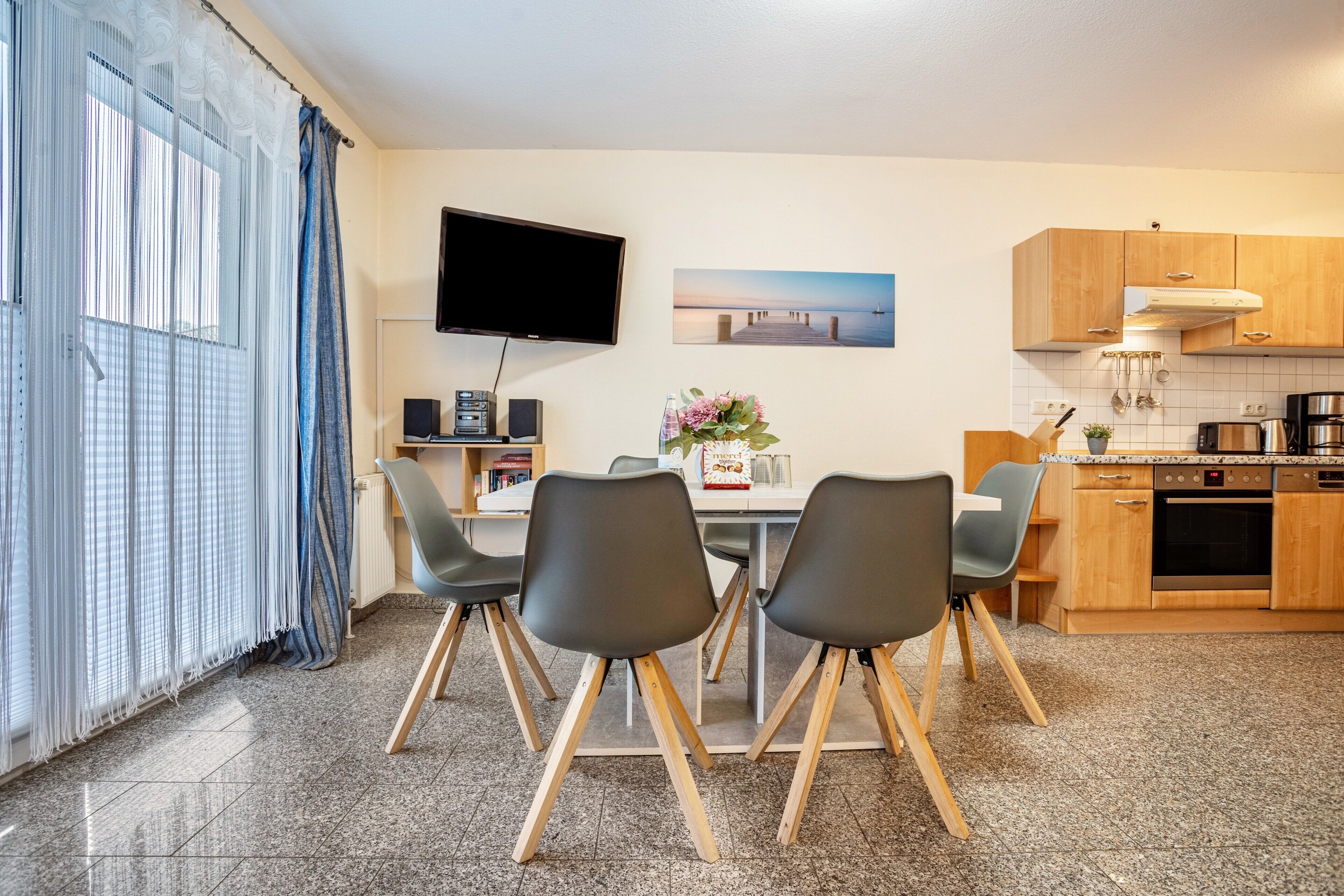 Eine moderne Küche mit Flachbildfernseher, Holzschränken und einer Essecke mit Stühlen.