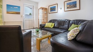 Een woonkamer met een leren bank, een glazen salontafel en een glazen kast met drinkgerei.