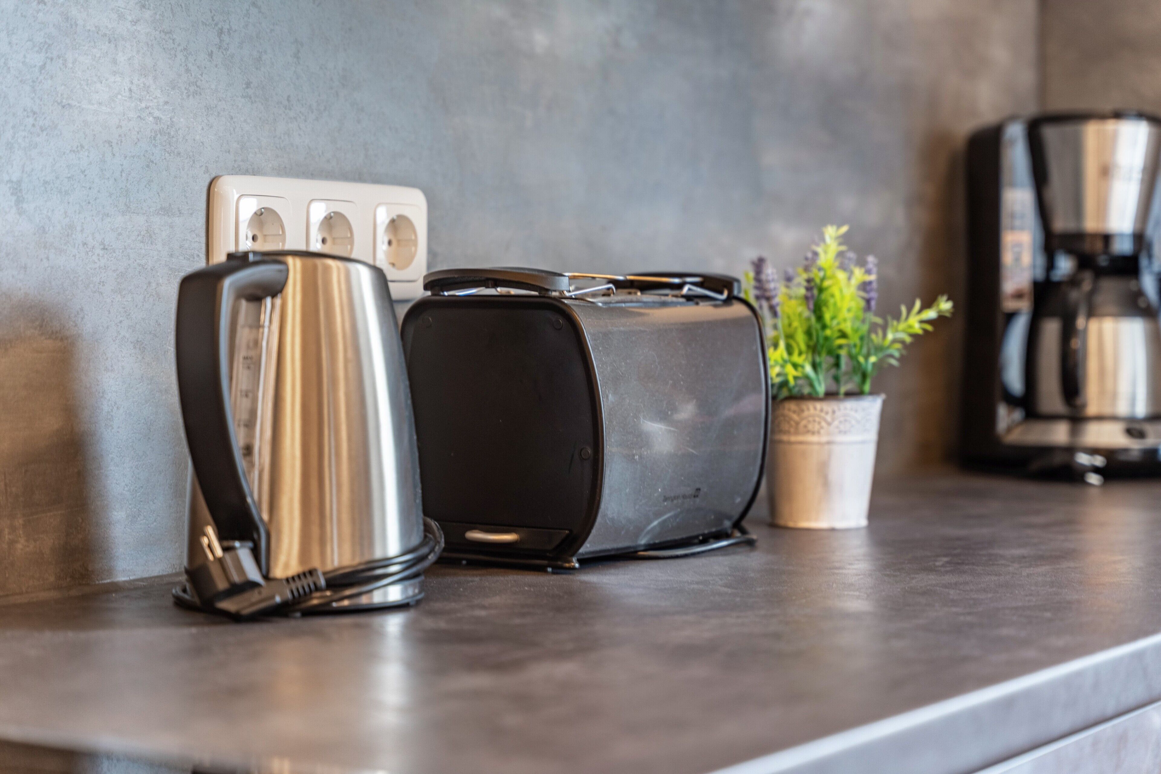 Un plan de travail de cuisine avec une bouilloire, un grille-pain et une machine à café.