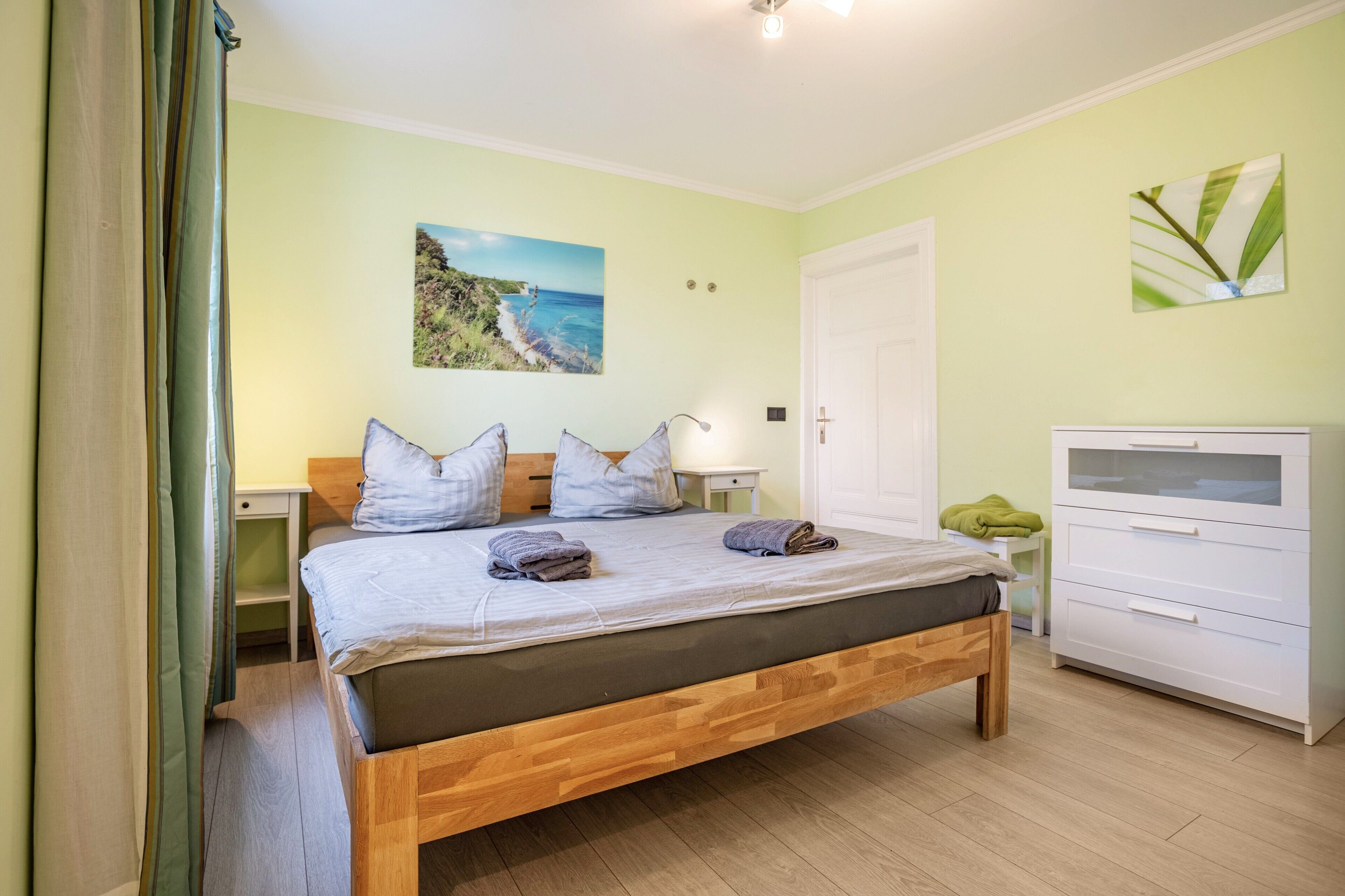 Une chambre à coucher comprenant un lit, des tables de chevet, une commode, une coiffeuse et un tableau accroché au mur.