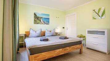Une chambre à coucher comprenant un lit, des tables de chevet, une commode, une coiffeuse et un tableau accroché au mur.