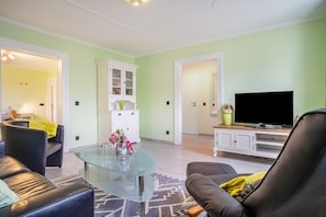A living room with a glass coffee table, a sofa, a television, and a cabinet.