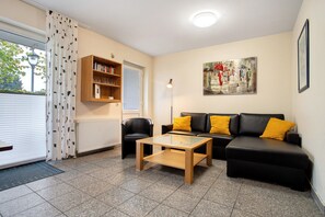 A living room with a sofa, a coffee table, a bookshelf, and a painting on the wall.