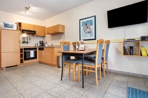 A kitchen with wooden cabinets, a microwave, a stove, and a dining table with chairs.