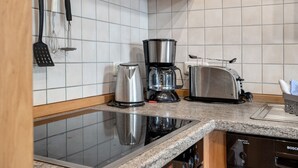 Una cocina con estufa integrada, cafetera, tostadora y lavavajillas.