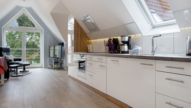 A modern kitchen with a skylight, white cabinetry, and a dining area with a view. - Apartment 'Bäckerhus - Ferienwohnung 4' with Private Terrace, Shared Garden and Wi-Fi (Wiek)