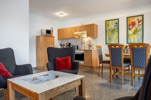 Une cuisine moderne avec des meubles en bois, un four à micro-ondes et un coin repas doté de chaises bleues.