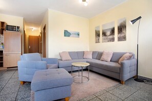 A living room with a sectional sofa, ottoman, and a small round table.