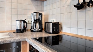 Une cuisine équipée d’une machine à café, d’un grille-pain et d’un four à micro-ondes, le tout posé sur le plan de travail.