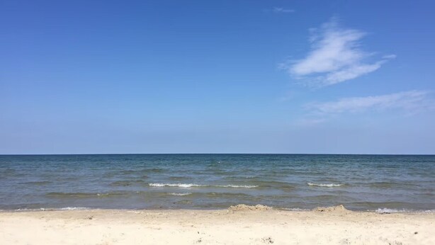 Une plage avec un ciel dégagé et une eau calme.
