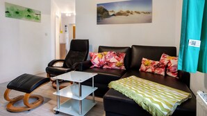 A living room with a sofa, chairs, a small table, and a painting on the wall. - Apartment 'Bäckerhus - Ferienwohnung 6' with Private Terrace, Shared Garden and Wi-Fi (Wiek)
