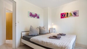 A bedroom with a bed, pillows, a bedside table, and wall art. - Apartment 'Bäckerhus - Ferienwohnung 6' with Private Terrace, Shared Garden and Wi-Fi (Wiek)