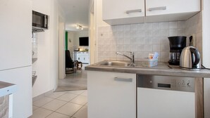 A modern kitchen with a dishwasher, a coffee maker, and a microwave. - Apartment 'Bäckerhus - Ferienwohnung 6' with Private Terrace, Shared Garden and Wi-Fi (Wiek)