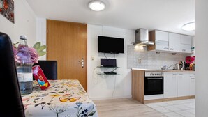 Una cocina moderna con armarios blancos, horno empotrado y un televisor de pantalla plana montado en la pared.
