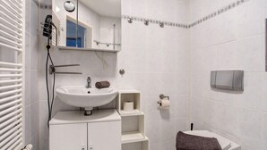 Un bagno con lavandino, specchio, porta asciugamani, servizi igienici ed erogatore di asciugamani.