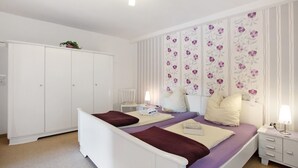 A bedroom with a bed, nightstands, a wardrobe, and a floral-patterned wall.