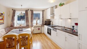 A kitchen with a dining area, white cabinets, a microwave, stove, and a sink.