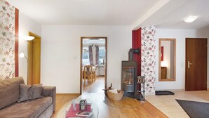 A living room with a sofa, a glass coffee table, a fireplace, and a view into the dining area.