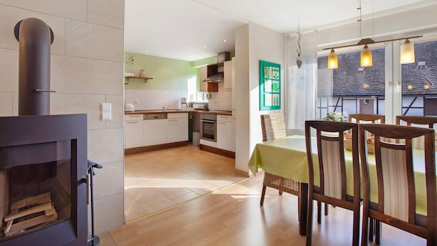 Una cocina moderna con estufa integrada, comedor con sillas y mesa, y vistas a la ciudad a través de amplios ventanales.