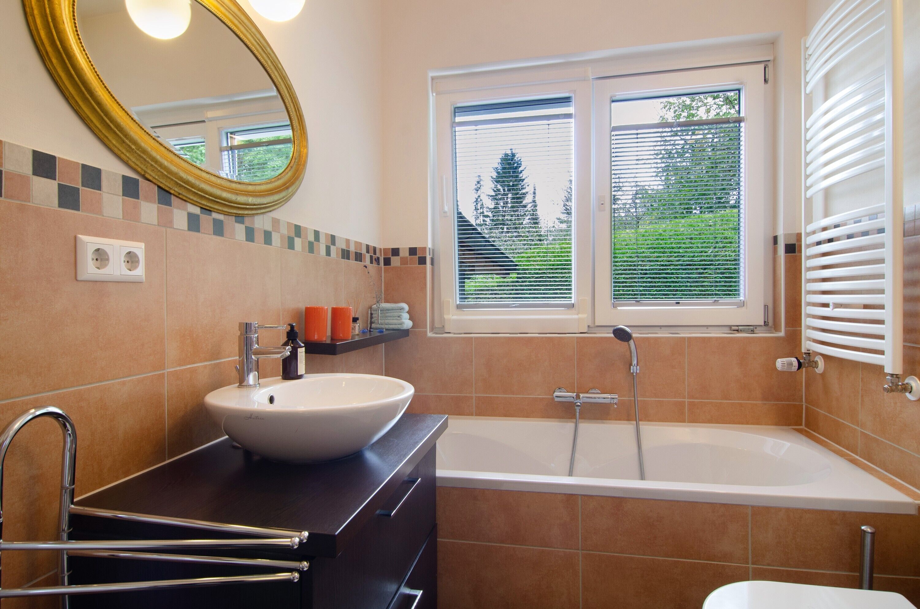 A bathroom with a bathtub, a sink, a mirror, and a window with blinds.