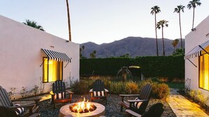 Une terrasse extérieure avec un foyer, des chaises et une vue sur les montagnes.