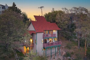 Une maison à deux étages avec un toit rouge, un balcon au deuxième étage et un escalier menant à l’entrée.