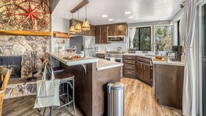 Una cocina moderna con pared de piedra, techo de madera y ventanas amplias.